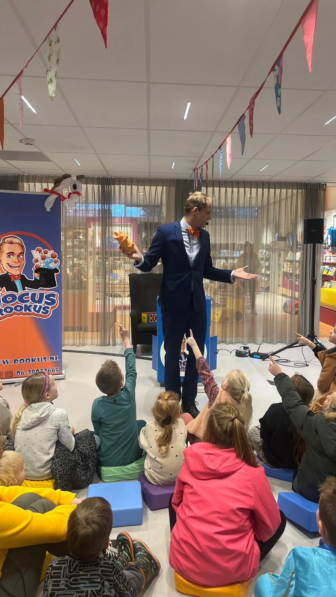 Kindergoochelaar Hocus Rookus toont goocheltruc aan groep kinderen