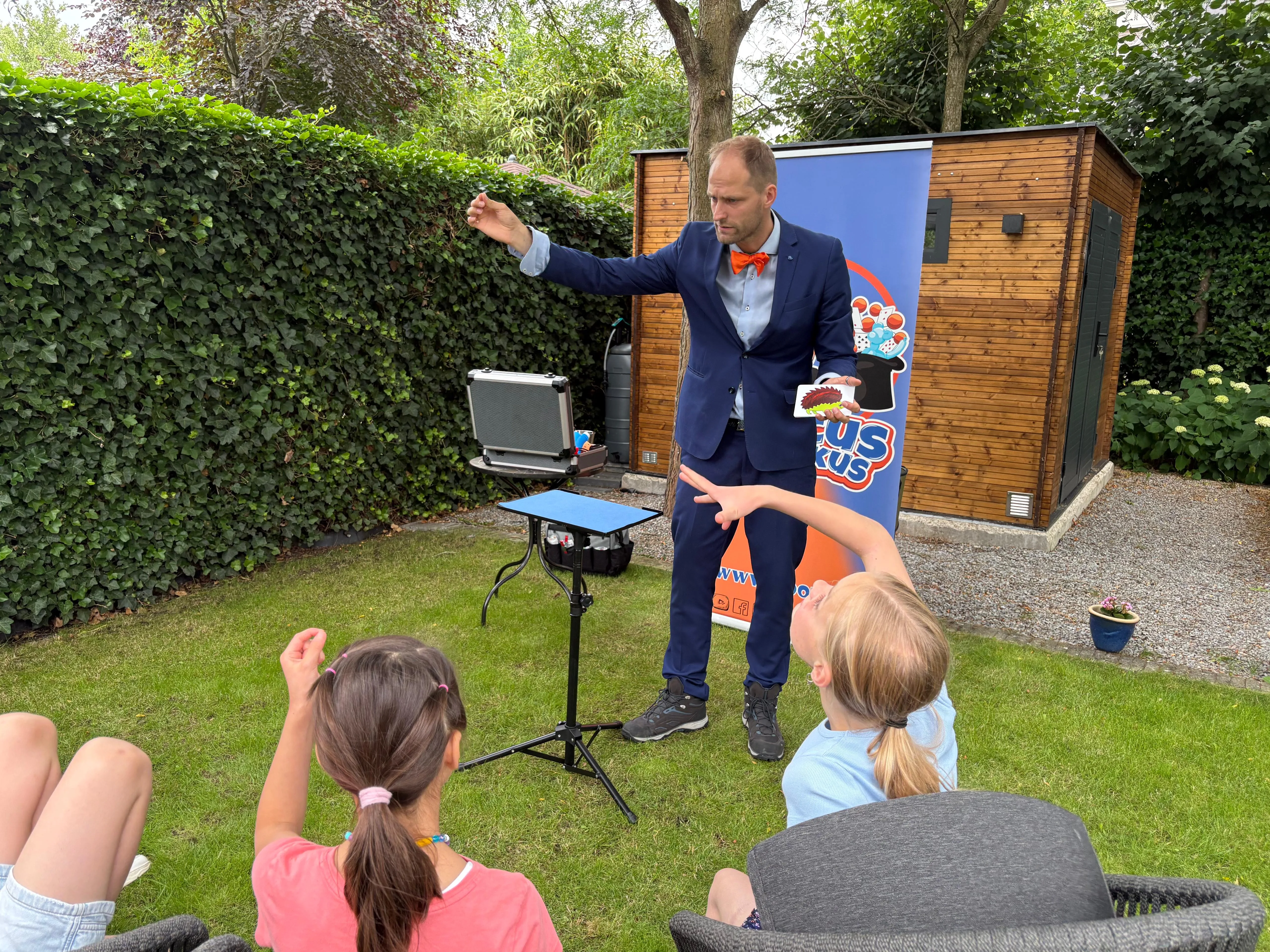 Hocus Rookus tovert voor twee meisjes tijdens kinderfeestje in de tuin